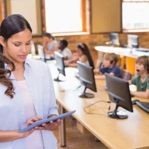 A woman is holding her tablet in front of some people.