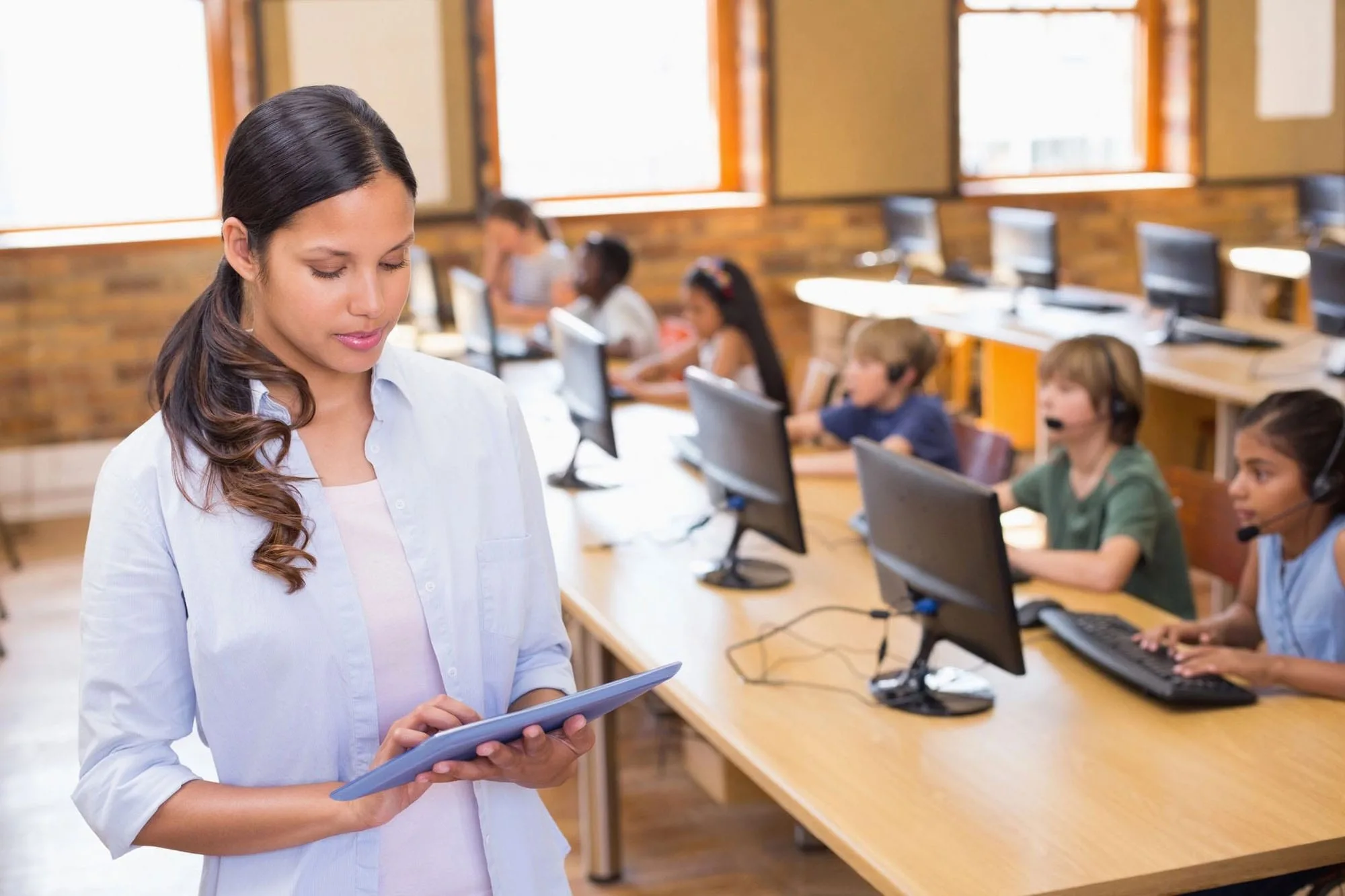 A woman is holding her tablet in front of some people.
