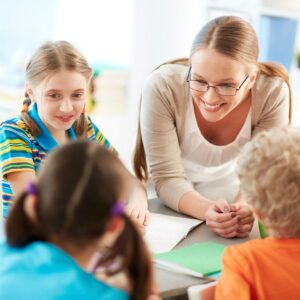 A woman and two children are sitting in front of papers.