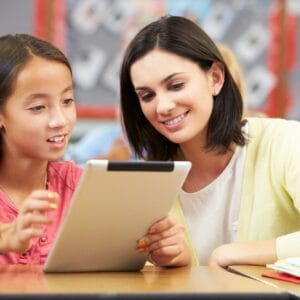 A woman and girl looking at an ipad.