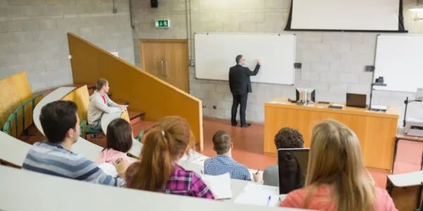 A group of people sitting in front of a white board.