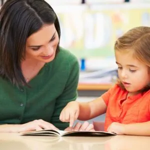A woman and girl looking at an open book.
