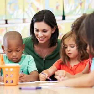 A woman is helping children with their writing.