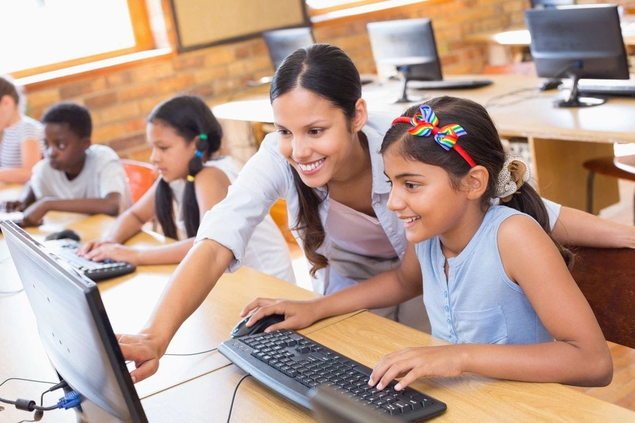 A woman and two girls are using a computer.